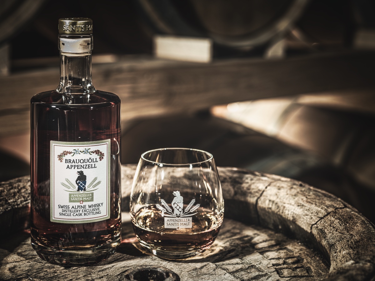 Whiskyflasche Brauquöell Appenzell und gefülltes Tasting-Glas auf einem Holzfass