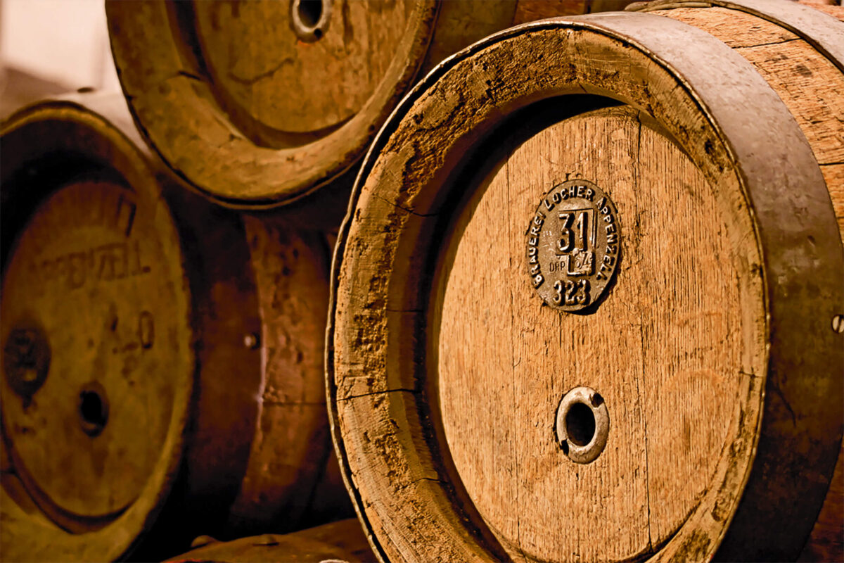 Detailaufnahme von aufeinandergestapelten Whiskyfässern im Keller